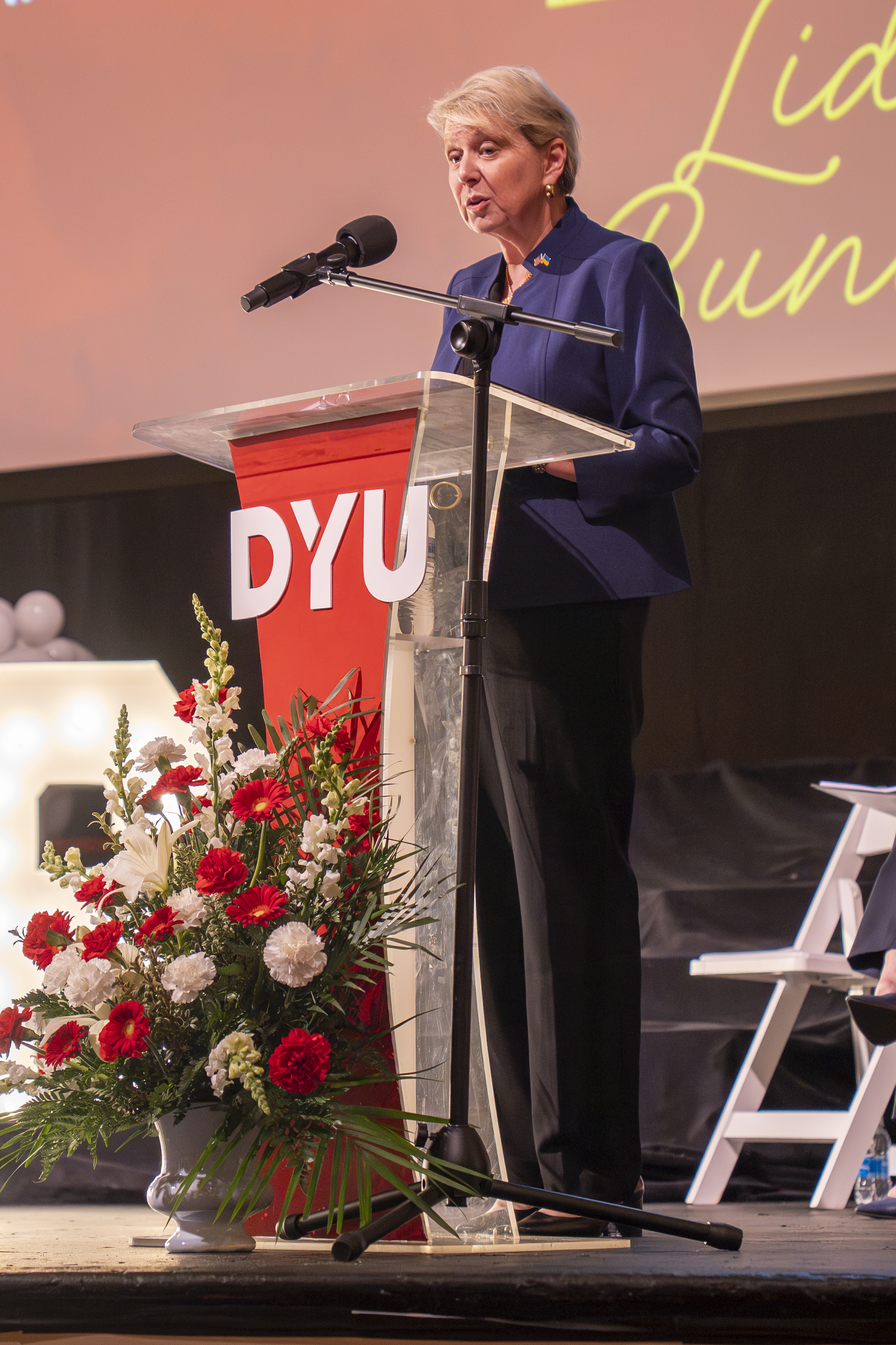 woman stands at a podium speaking into a microphone