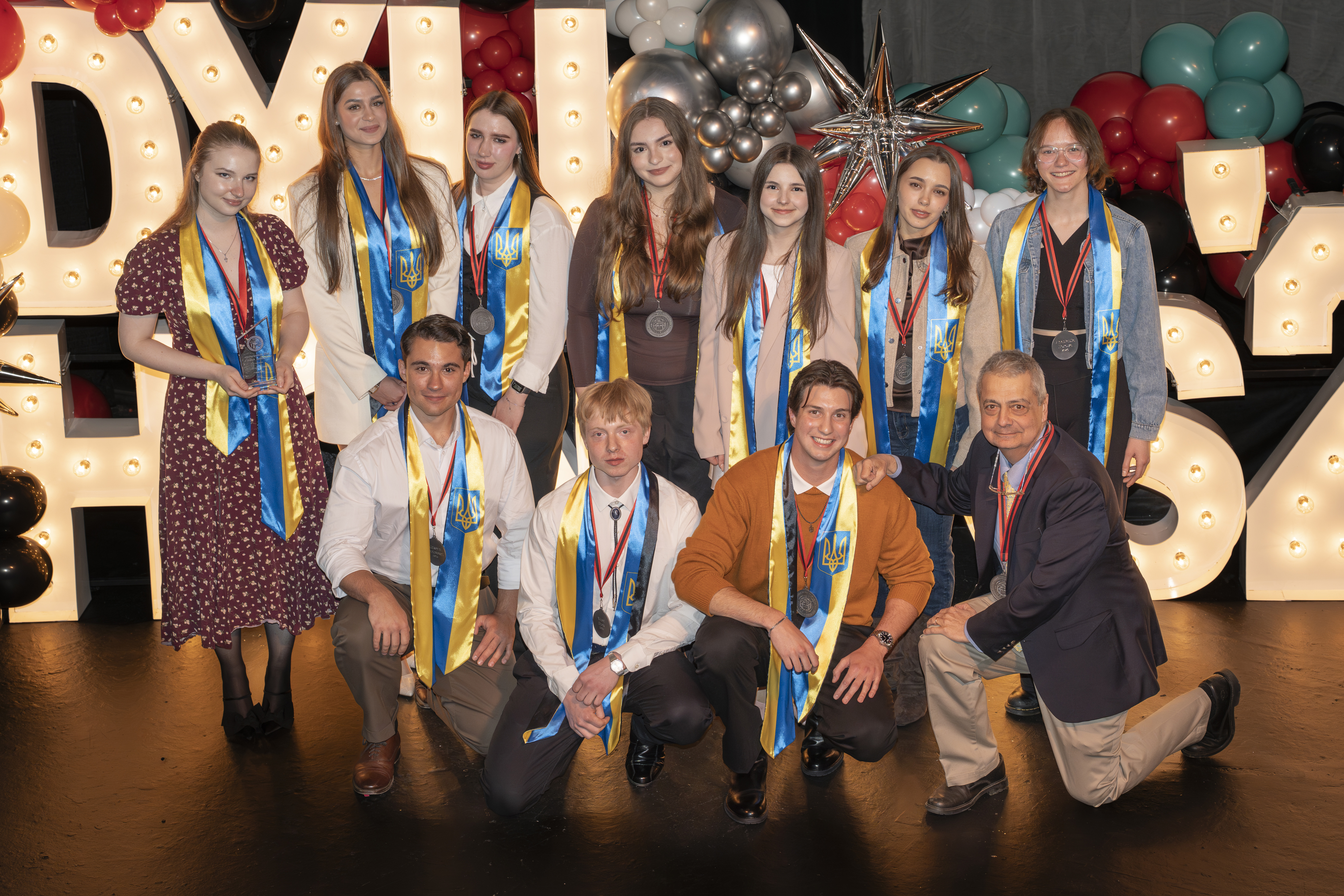 group stands on stage smiling at the camera