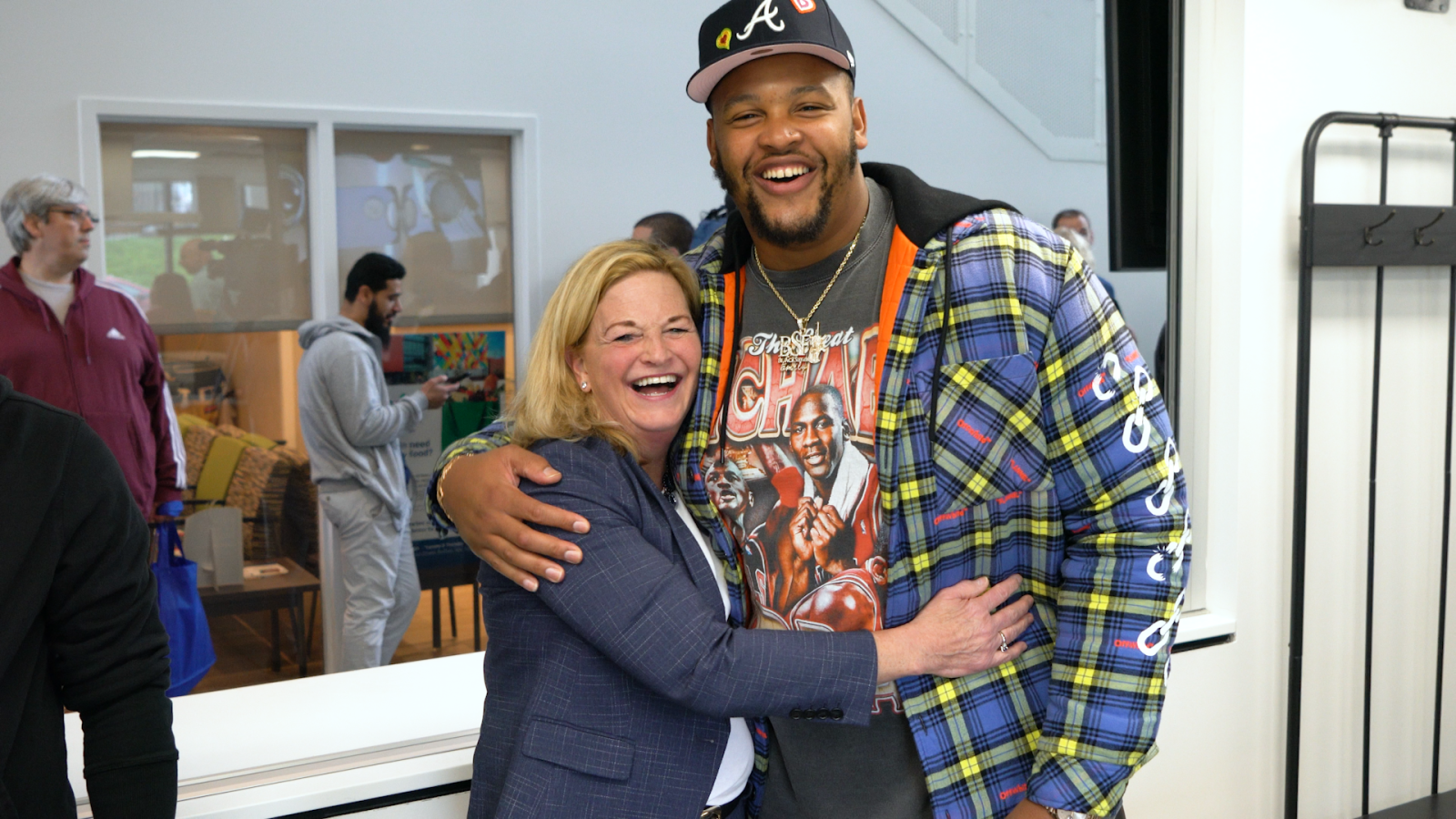 Dion Dawkins and President Lorrie Clemo greet each other at event. You see people behind them through a large wall opening.