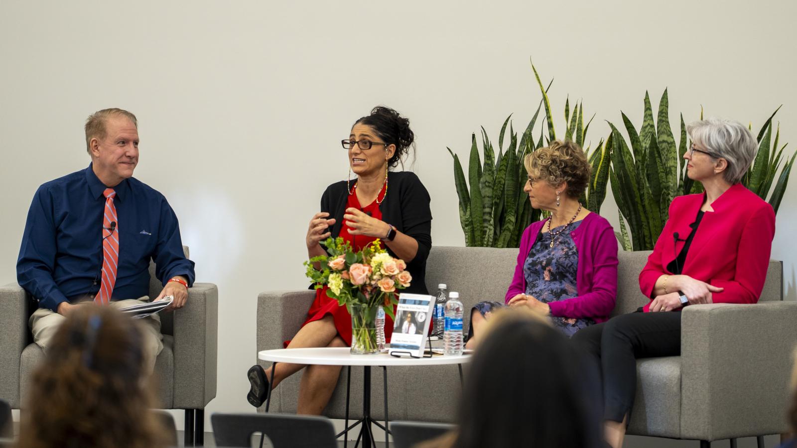 Three women sit on a stage for a panel discussion.