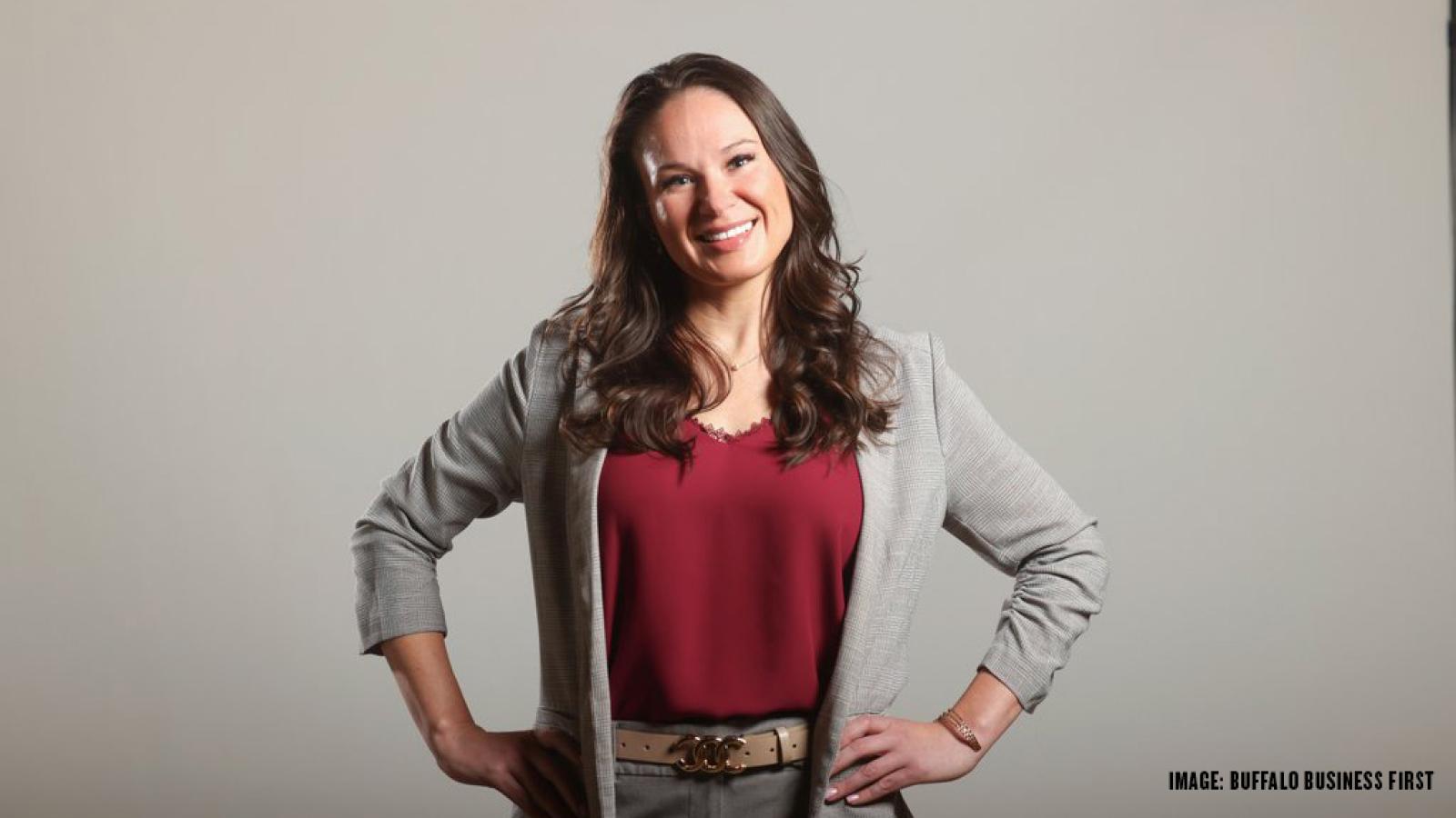 woman stands with hands on hips smiling at the camera