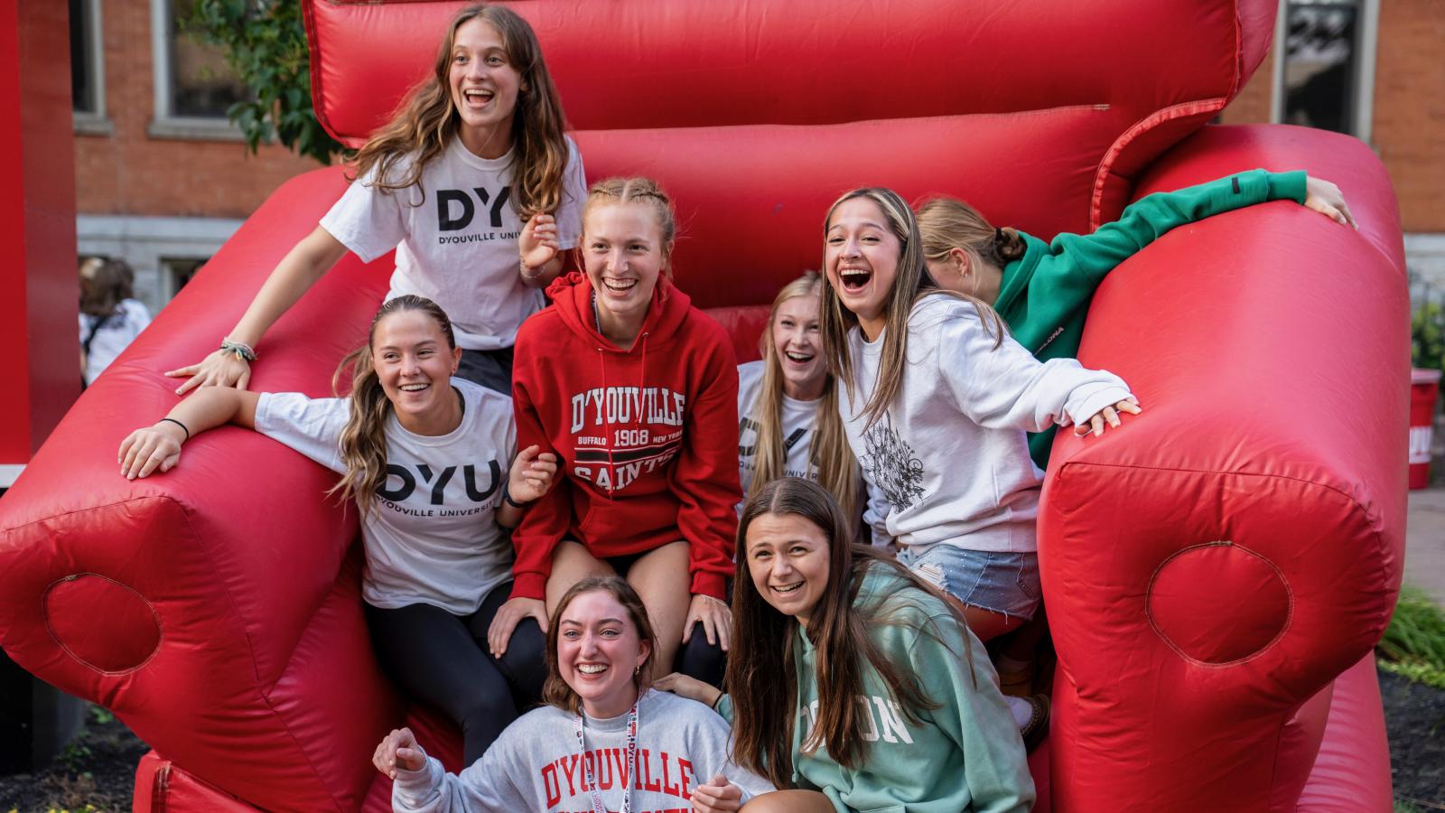 a large group of students sitting on a giant red inflatable chair smiling and laughing