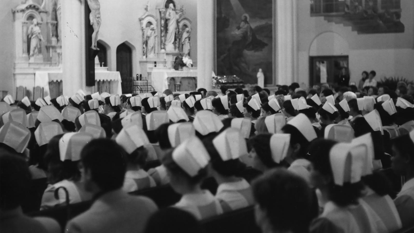 View from the back of a church looking at rows of nurses in their caps at their capping ceremony