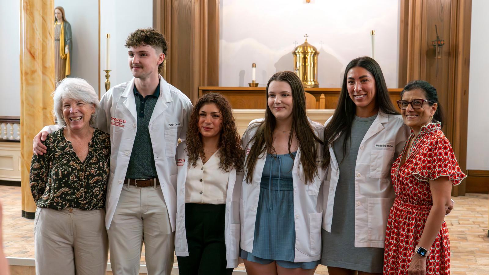 a line of people stand smiling at the camera