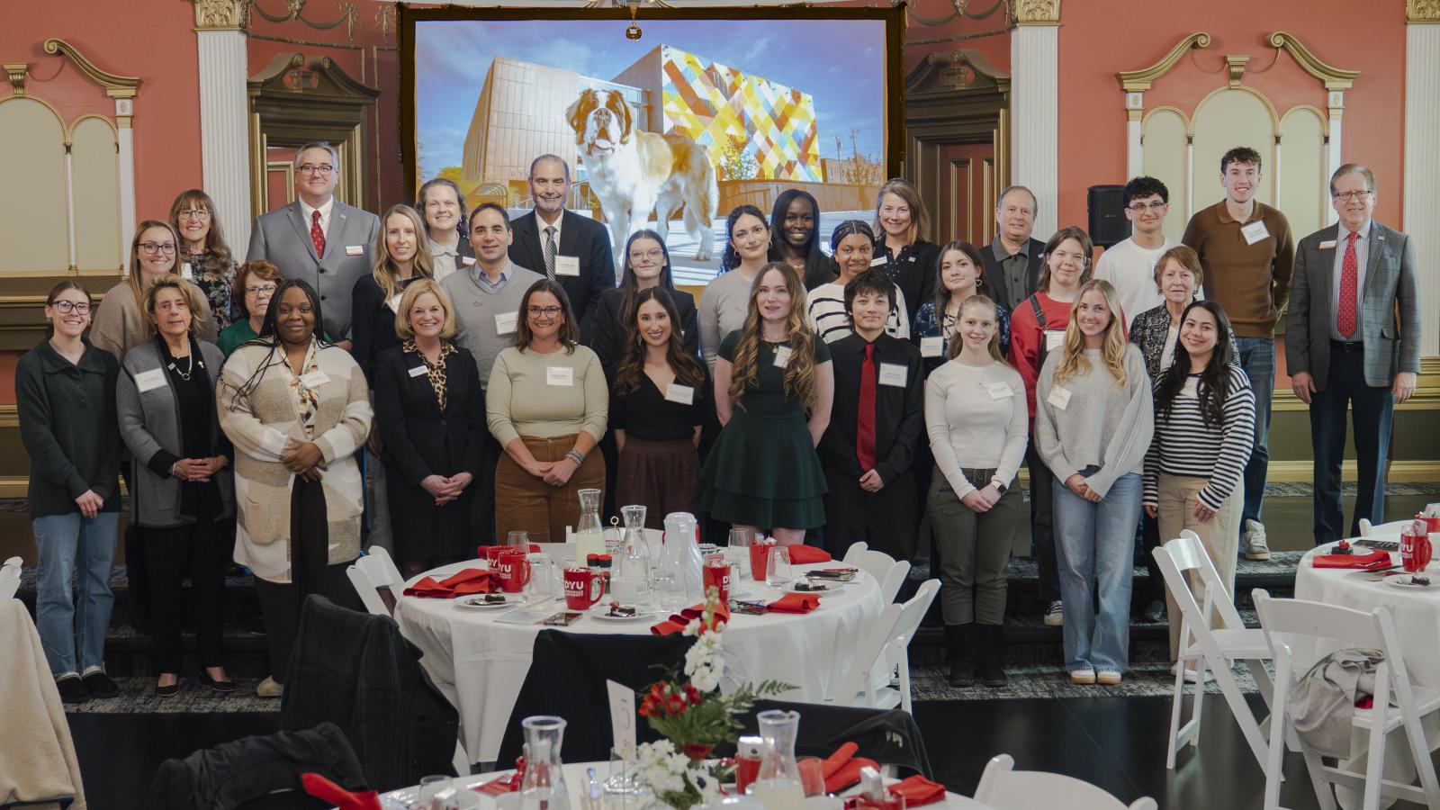A large group of people stand on a stage smiling at the camera