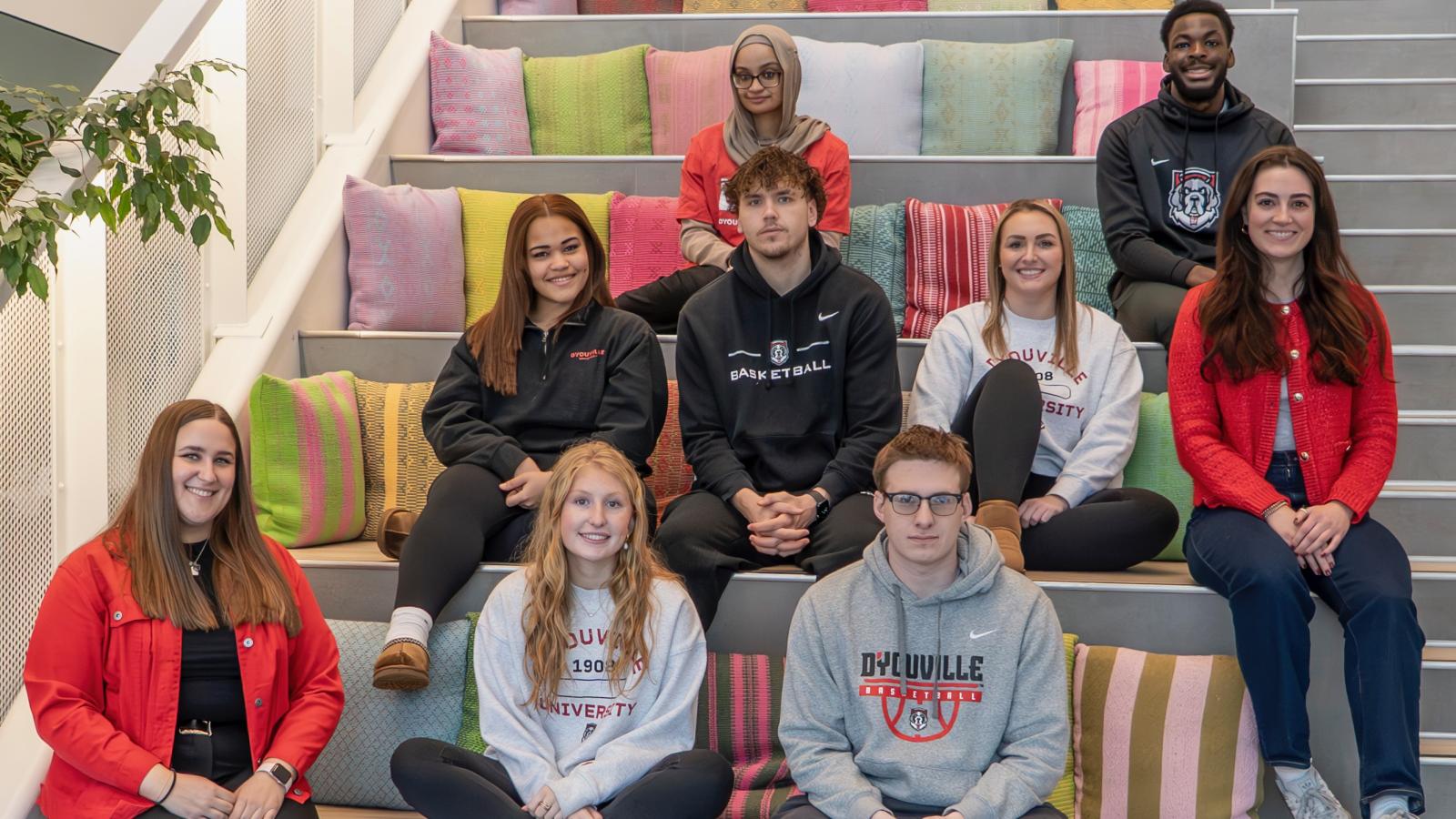 A group of nine students seated on steps smiling at the camera