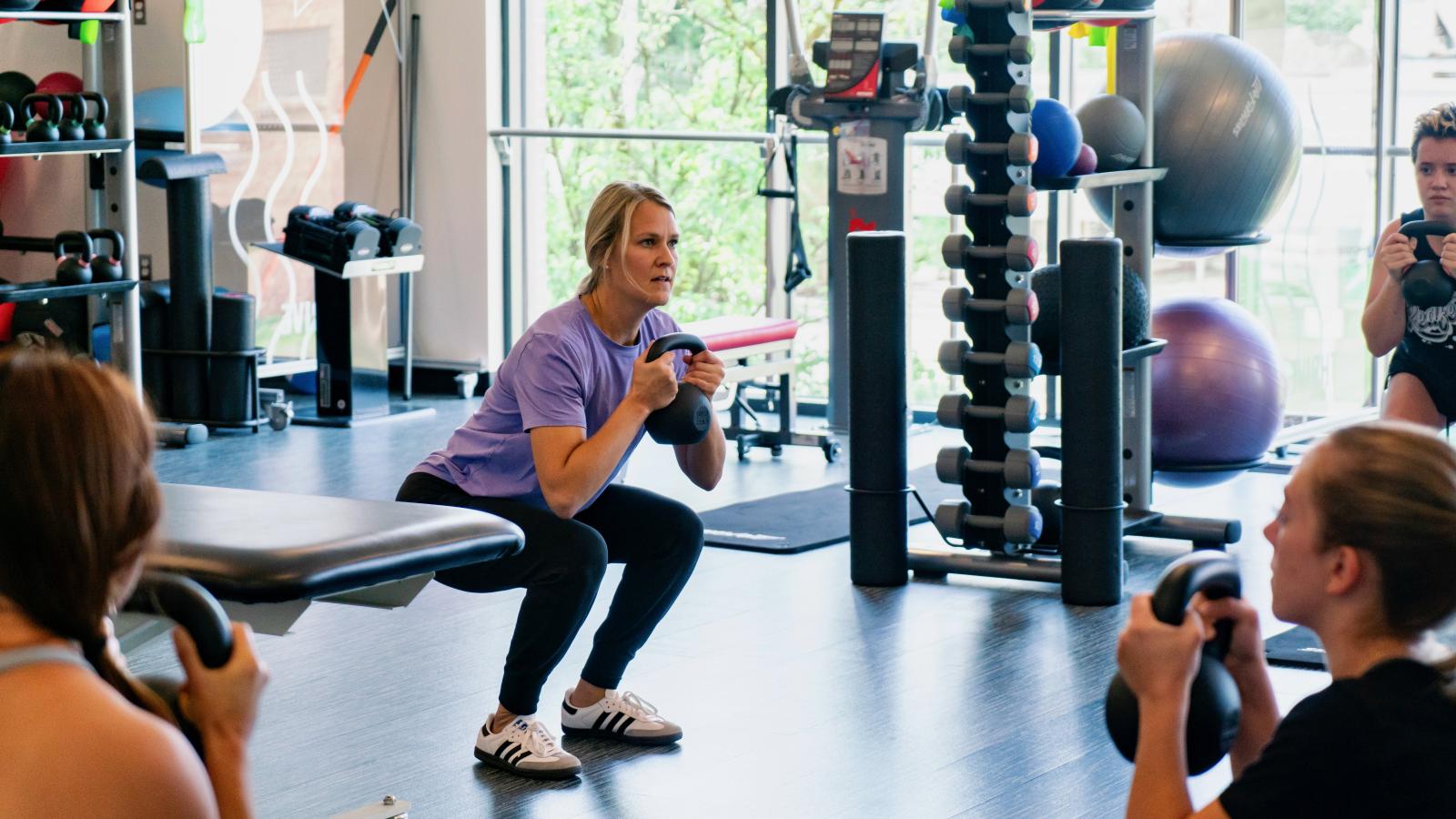 woman squatting with a kettlebell in a gym