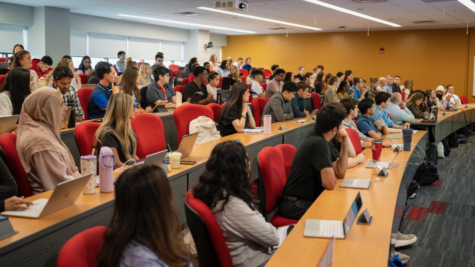 students seated at long lecture hall tables