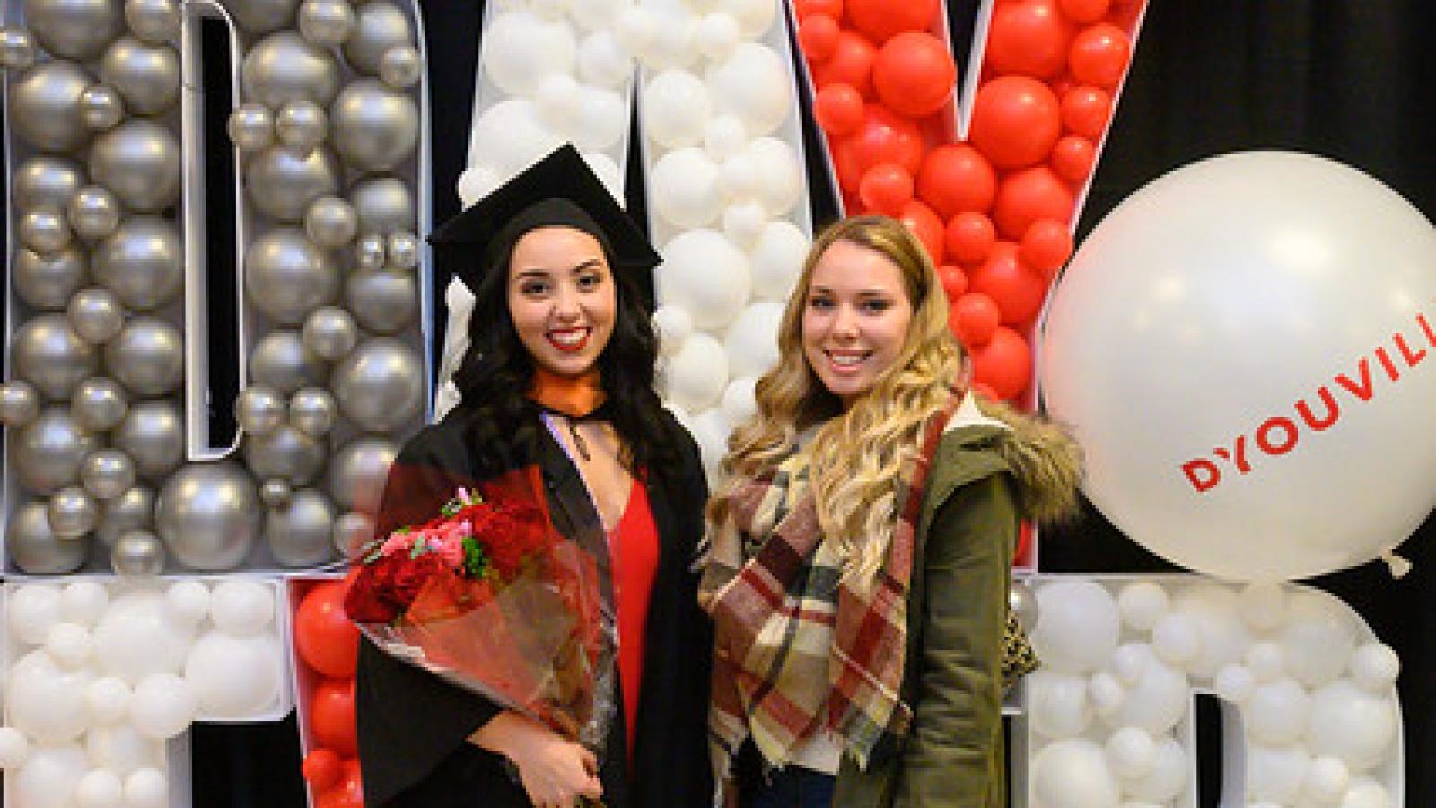 Two female students stand in front of a Best Day ever balloon display.