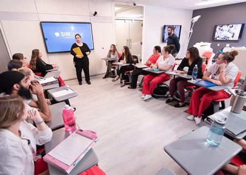 Students sitting at desks listening to a lecture inside the IPE simulation center.