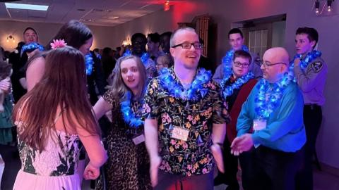 Individuals dancing in a group inside a banquet hall