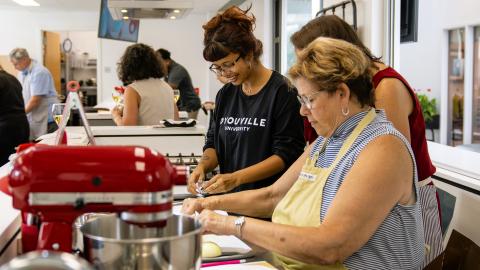 student smiling while participating in a cooking demonstration