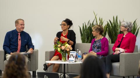 Three women sit on a stage for a panel discussion.