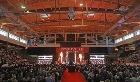A large arena. stage in front with two screens on either side. large banner reads D'Youville.