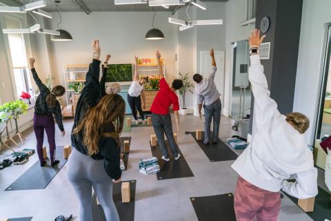 group of people standing on yoga mats and stretching