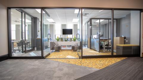 Looking into glass walled office with desks and chairs
