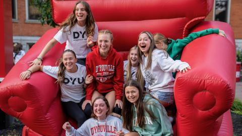 a large group of students sitting on a giant red inflatable chair smiling and laughing