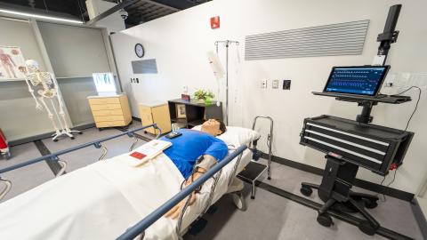 medical manikin lays in a hospital bed.