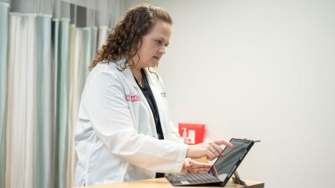 Shannon mcCory-Churchill stands in medical space using a tablet