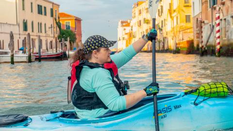 woman in kayak rowing on Venetian canal 