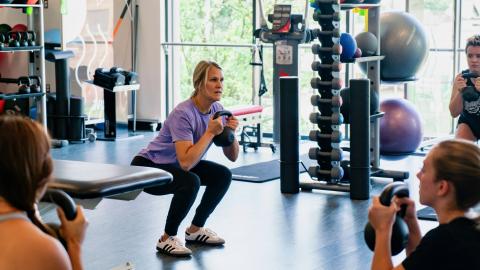 woman squatting with a kettlebell in a gym