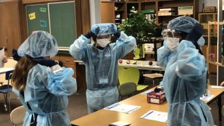 Three students putting on personal protective equipment at a camp