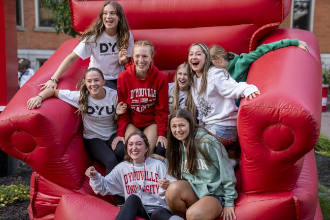 a group of young people sit together laughing on a giant red inflatable chair