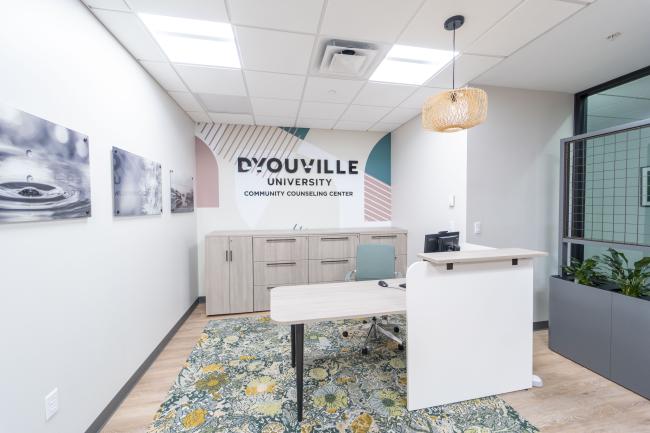 Check in desk in a office waiting room. There is a sign on the wall that reads D'Youville University Community Counseling Center.