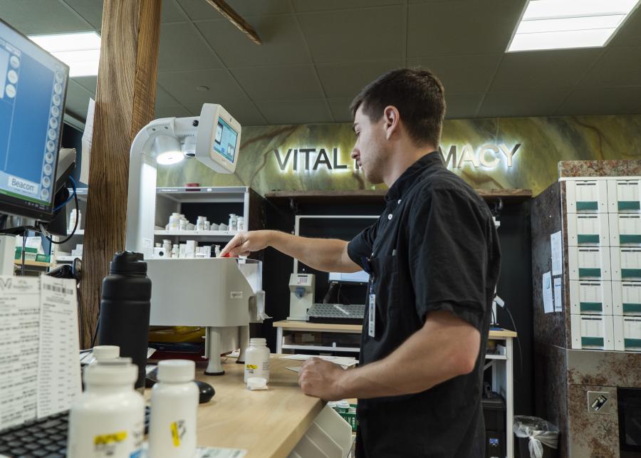 Young male counting pills to fill a prescription inside vital pharmacy
