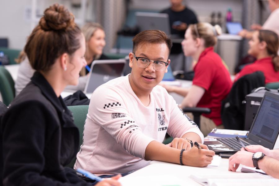 Student talking to a peer in a classroom.