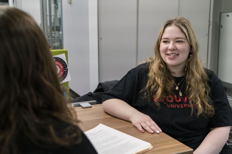 Young woman sitting at a desk smiling at a counselor 