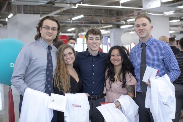 Student smiling while holding new white coats.