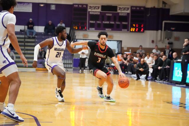 Man in D'Youville Uniform dribbling basketball