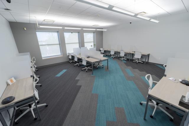 White and grey room with many long tables with desk dividers.