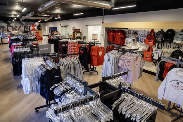 Racks of clothing with D'Youville University logos.