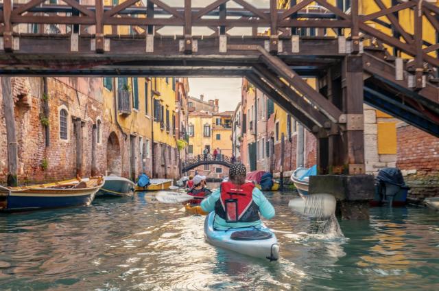 group of kayaks traveling through venetian canal