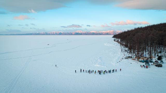 aerial shot of many people gathered in a wide flat snowy landscape