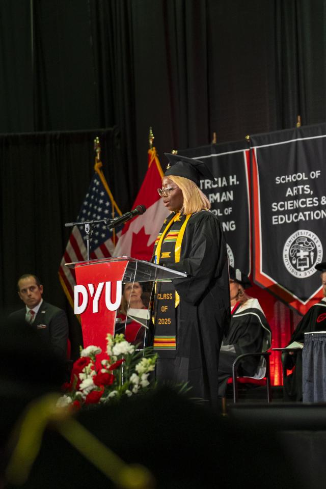 Nangie Alexander stands at a podium in front of a large audience