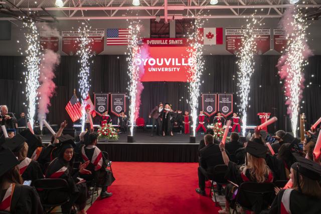 looking down a center aisle as pyrotechnics go off on a stage 