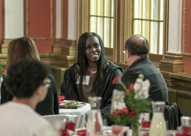 woman seated at a round banquet table speaking to another guest
