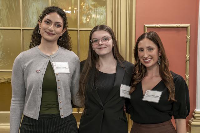 Three woman stand together smiling at the camera