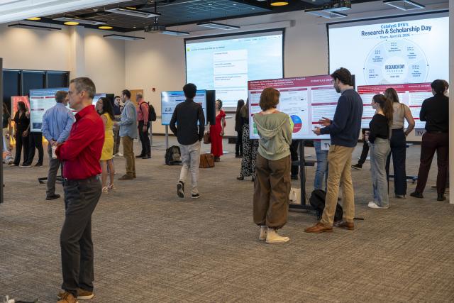 large room with many people standing and talking at individual research posters