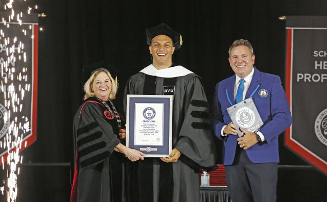 Dr. Lorrie Clemo, Mack Hollins, and Michael Empric stand on stage with official GUINNESS WORLD RECORDS award.