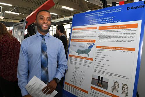 a student stands in front of a poster presentation.