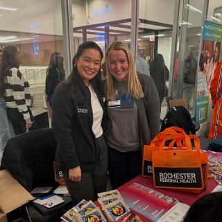 two women stand behind a table and smile at the camera