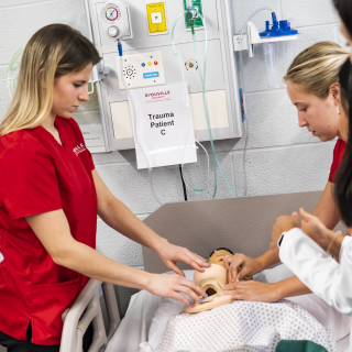 group of nursing students working with a manikin with a neck brace