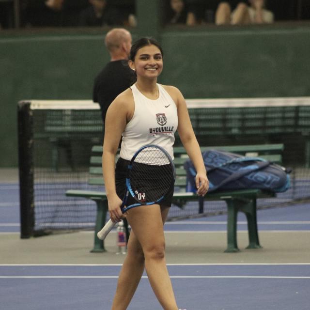 Khushi Agarwal, woman smiles at the camera wearing D'Youville University tennis uniform.